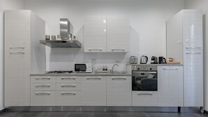 Una cocina moderna con armarios blancos, estufa a gas, horno empotrado y cafetera.