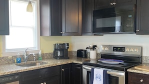 A modern kitchen with dark cabinetry, stainless steel appliances, and a granite countertop.