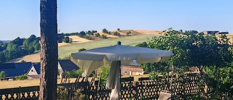 Un patio con una mesa y sillas, un árbol y vistas a un paisaje rural.