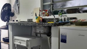 Une cuisine équipée d’un four à micro-ondes encastré, d’une petite table blanche et d ’une fenêtre située au-dessus de l’évier.