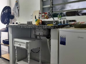 Eine Küche mit einer eingebauten Mikrowelle, einem kleinen weißen Tisch und einem Fenster über der Spüle.