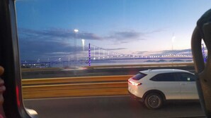 Un véhicule sur une route, avec un pont en arrière-plan.