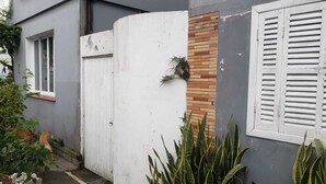 Un immeuble résidentiel avec une porte blanche, un mur en briques et une fenêtre avec des volets.