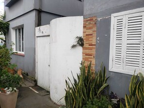 Ein Wohngebäude mit einer weißen Tür, einer Ziegelwand und einem Fenster mit Rollläden.