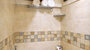 A bathroom with a toilet, a shower, and a towel rack with towels. - Glitz Saineel Executive Near Juhu Beach (Mumbai)