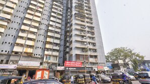 A multi-story building with balconies, a sign for 'Hotel Sainedi Residency', and various shops at the ground level. - Glitz Saineel Executive Near Juhu Beach (Mumbai)