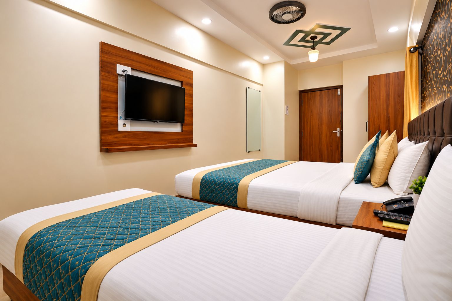 Habitación de hotel con dos camas, televisión, espejo y puerta de madera.