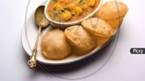 A plate with a bowl of curry and two bread rolls. - Glitz Saineel Executive Near Juhu Beach (Mumbai)