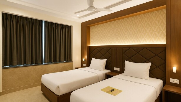 A hotel room with two single beds, a ceiling fan, a window with curtains, and a patterned wall. - Glitz Saineel Executive Near Juhu Beach (Mumbai)
