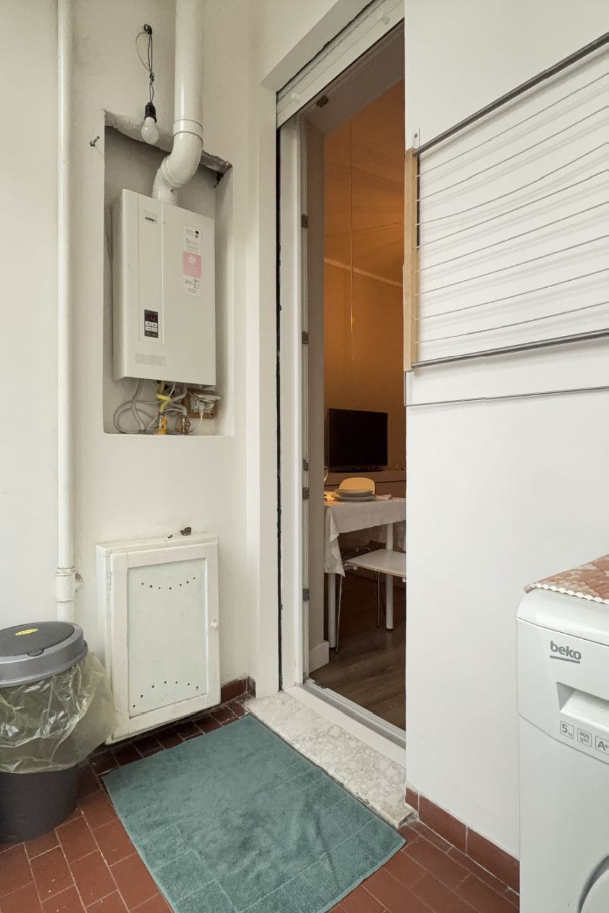 Ein Hauswirtschaftsraum mit Warmwasserbereiter, Waschmaschine und Mülleimer.
