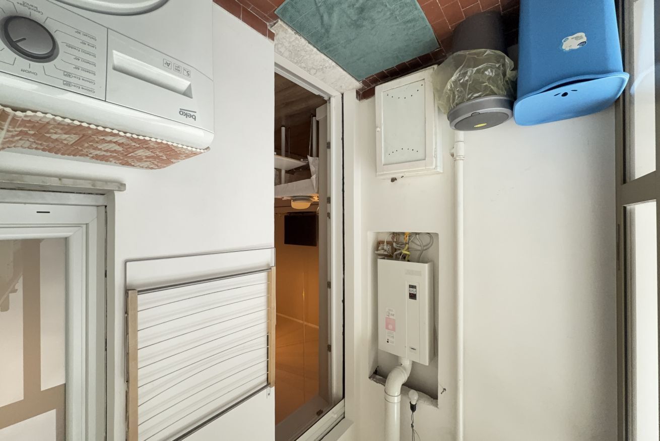 Una habitación con un equipo de aire acondicionado blanco, una ventana con persianas y un cubo de basura azul.