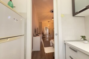 Una cocina moderna con refrigerador, un comedor con mesa y sillas, y una planta pequeña en la encimera.