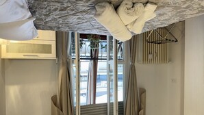Een slaapkamer met een bed, een raam met gordijnen, een radiator en een hanglamp.