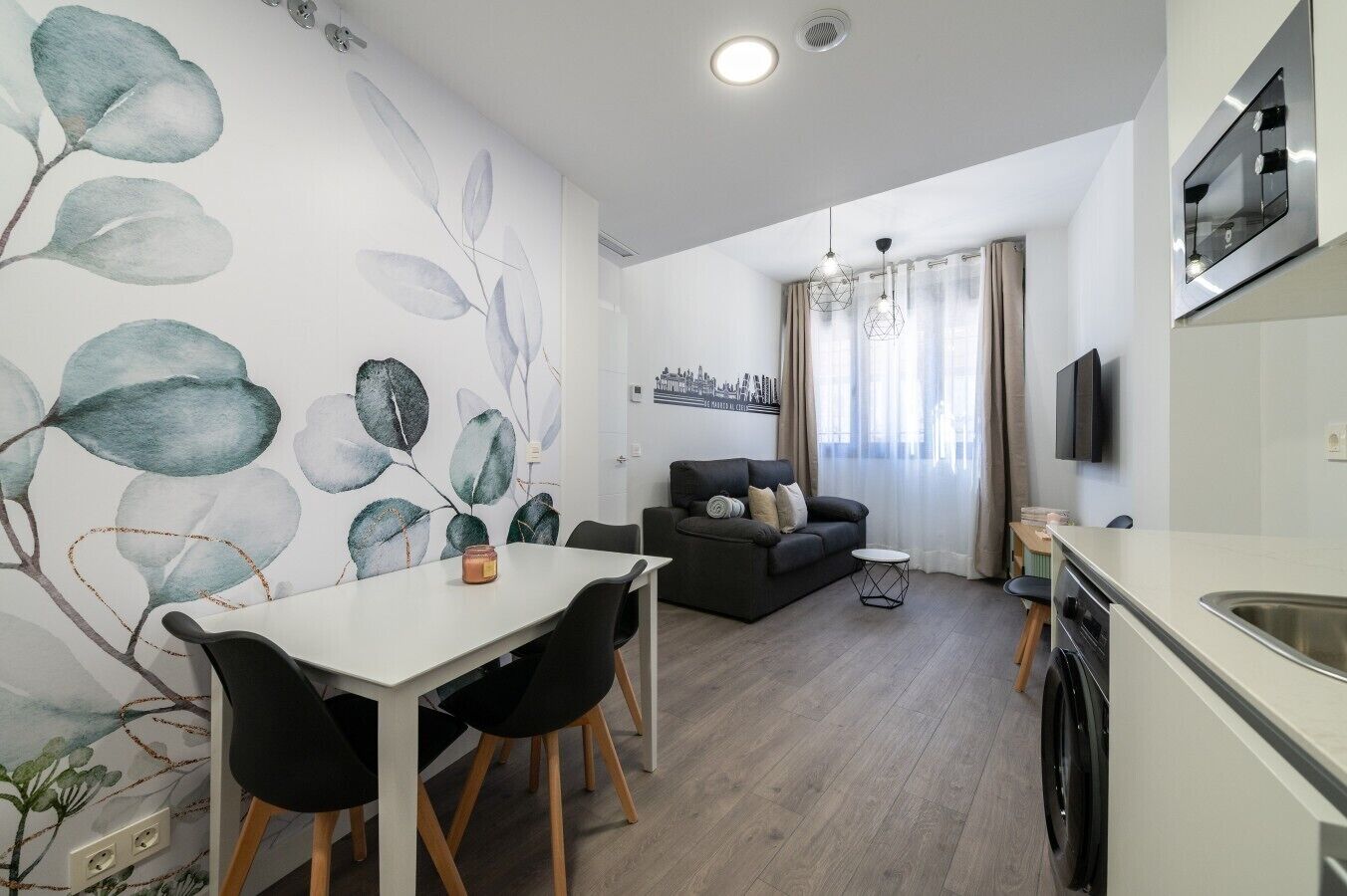 Un espace de vie moderne comprenant un coin repas, un canapé, une cuisine et une grande fresque murale.