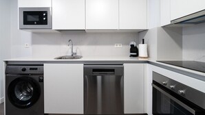 Una cocina moderna con electrodomésticos de acero inoxidable, microondas integrado, lavavajillas y lavadora.