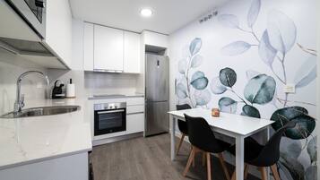 A modern kitchen with white cabinetry, a built-in oven, and a stainless steel refrigerator.