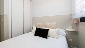Una habitación de hotel con cama, mesita de noche, lámpara y armario.