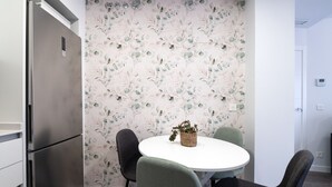 Una cocina moderna con un refrigerador de acero inoxidable, una mesa redonda con cuatro sillas y un papel tapiz floral.