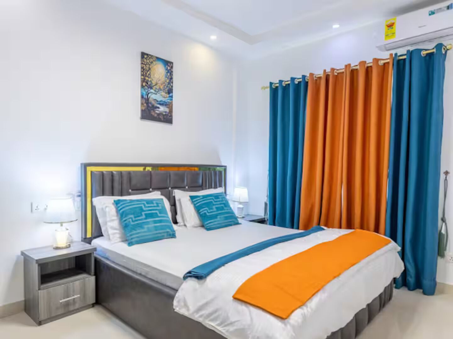 Een moderne hotelkamer met een bed, nachtkastjes en een schilderij aan de muur.