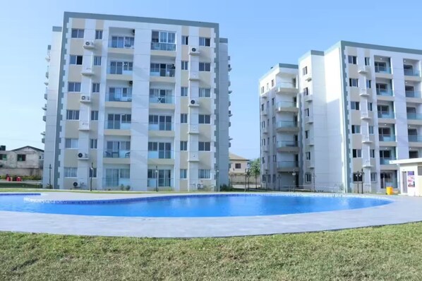 A modern apartment building with multiple floors, balconies, and air conditioning units.