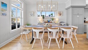 A modern kitchen with a central island, white chairs, and a chandelier. - Heavenly Sunset - Private Pool and Putting Green! (Bradenton Beach)