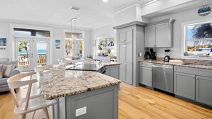 A spacious kitchen with granite countertops, grey cabinetry, and a large island. - Heavenly Sunset - Private Pool and Putting Green! (Bradenton Beach)