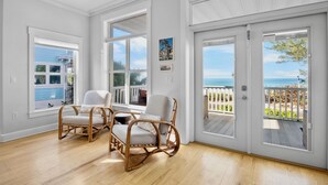 A bright room with large windows, a wicker chair, and a view of the ocean. - Heavenly Sunset - Private Pool and Putting Green! (Bradenton Beach)