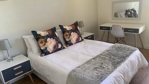 A neatly arranged bedroom with a bed, two nightstands, a desk, and a chair. - Lovely flat, walk to Glentana beach... Play golf! (Great Brak River)