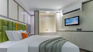 A modern hotel room with a large bed, a green upholstered headboard, a flat-screen TV mounted on the wall, and a built-in air conditioning unit. - Yueduo Selected Hotels (Guangzhou)
