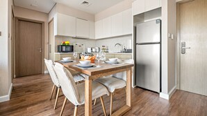 A modern kitchen with white cabinets, a wooden dining table, and a stainless steel refrigerator. - Downtown Dubai Chic 1BR Retreat (Dubai)