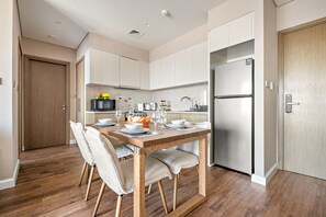 Eine moderne Küche mit weißen Schränken, einem Holztisch und einem Edelstahlkühlschrank.