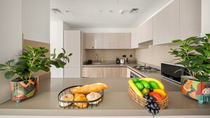A modern kitchen with a central island, built-in appliances, and potted plants. - Stylish 2BR + Maid’s Apartment in Sobha Hartland (Dubai)