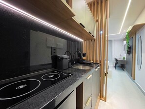 Eine moderne Küche mit schwarzem Arbeitsplatz, integrierten Geräten und einem Essbereich mit Tisch und Stühlen.