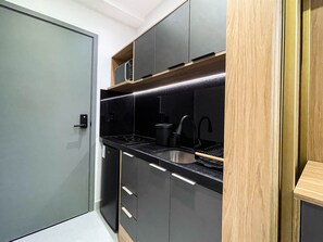 A compact kitchen with a black countertop, stainless steel sink, and modern cabinetry. - Solaz by Hosppedar (João Pessoa)