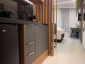 A modern kitchen with a built-in refrigerator, wooden cabinets, and a dining area with a table and chairs. - Solaz by Hosppedar (João Pessoa)