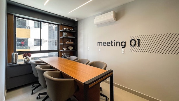 A modern meeting room with a long table, chairs, a bookshelf, and a wall-mounted air conditioner. - Solaz by Hosppedar (João Pessoa)