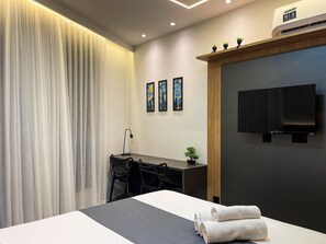 A modern hotel room with a bed, a desk, a chair, a TV, and artwork on the wall. - Solaz by Hosppedar (João Pessoa)