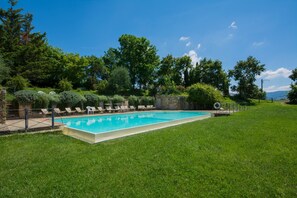 A rectangular swimming pool with a clear blue water surface, surrounded by a grassy lawn and a stone wall. - Holiday Home 'Romantica' with Shared Pool, Wi-Fi and Air Conditioning (Bagno a Ripoli)
