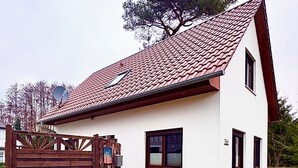 Een herenhuis met een rode dakbedekking, een houten poort en het nummer '350' op de muur.