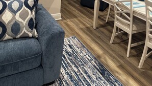 Ein modernes Wohnzimmer mit einem blauen Sofa, einem Essbereich mit weißen Stühlen und einer Küche mit einer weißen Kochinsel.
