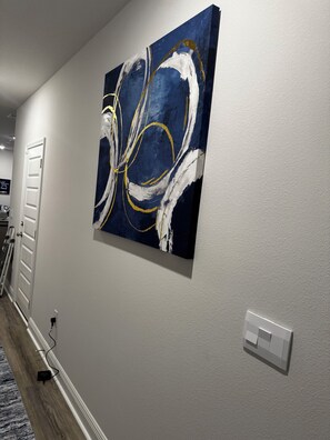Ein Flur mit einem großen abstrakten Gemälde an der Wand, einer Tür und einer Steckdose.
