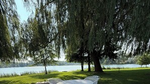 Eine Terrasse mit einem runden Tisch und Stühlen, mit Blick auf einen See.