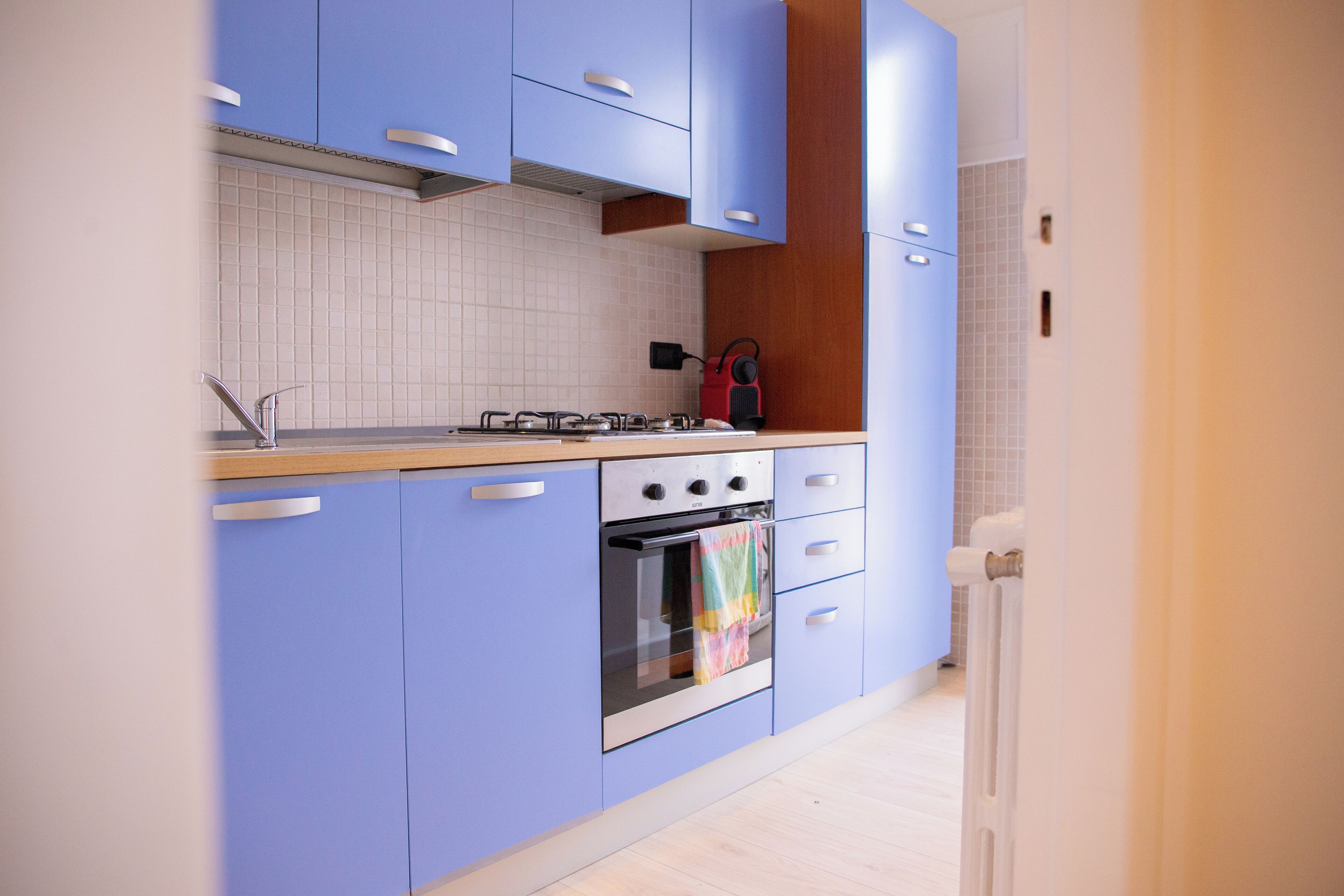 A kitchen with blue cabinets, a gas stove, an oven, and a tiled backsplash.