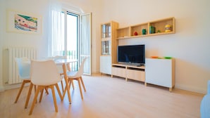 A modern living room with a dining area, a TV, and a bookshelf. - Solemar Sicilia-Vista Mare Alla Cala  (Palermo)