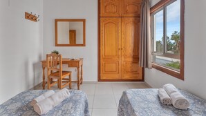 A room with two beds, a desk, a chair, a wardrobe, a mirror, and a window. - Infinity Pool Views 2 with Shared Pool, Private Terrace, and Wi-Fi (Playa de las Américas)