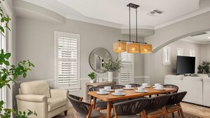A dining area with a wooden table set for six, surrounded by wicker chairs. - Reunion villa w/ pool & cinema room (Kissimmee)