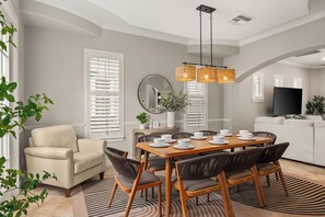 Un coin repas avec une table en bois dressée pour six personnes, entourée de chaises en osier.