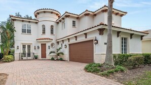 A large, two-story house with a curved front, a brown garage door, and a brick driveway. - Reunion villa w/ pool & cinema room (Kissimmee)