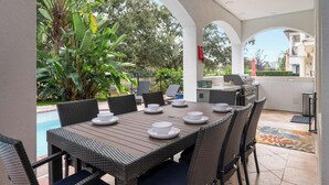 An outdoor patio with a dining table set for four, surrounded by wicker chairs. - Reunion villa w/ pool & cinema room (Kissimmee)