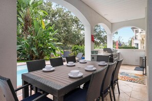 Une terrasse extérieure avec une table à manger pour quatre personnes, entourée de chaises en osier.